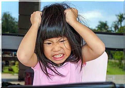 Angry little girl with her hands on her head pulling her hair.