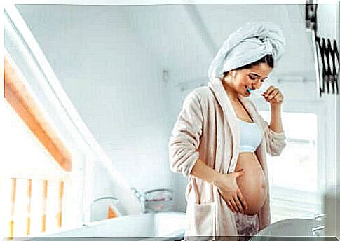 Pregnant woman brushing her teeth in the bathroom.