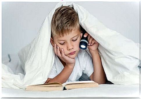 Child studying in bed with flashlight