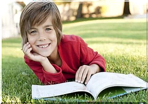 Smiling child reading a book in a park.