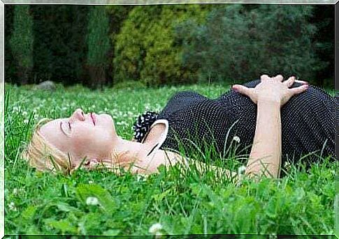 Woman is lying pregnant on a meadow.