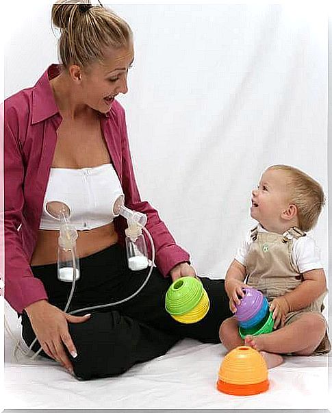 Mom using breast pump while playing with baby