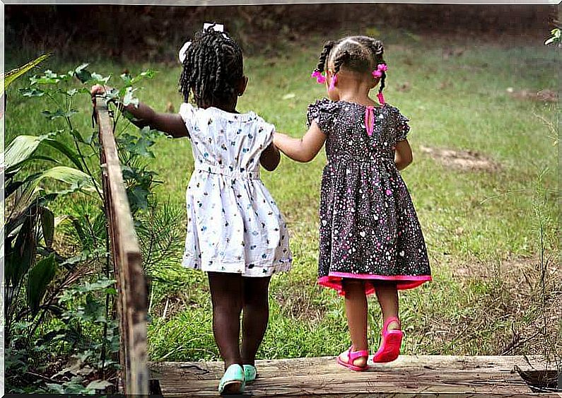 Two little girls stroll holding hands